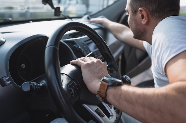 Volwassen man autodashboard schoonmaken met een doek