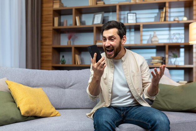 Volwassen man die de overwinning en succesvolle prestatie viert, kreeg een online nieuwsbericht op de app met behulp van de telefoon