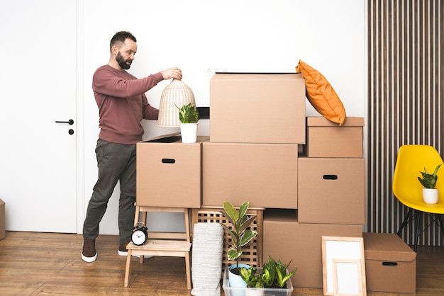 Foto volwassen man die dingen uit dozen uitpakt terwijl hij naar een nieuw appartement verhuist