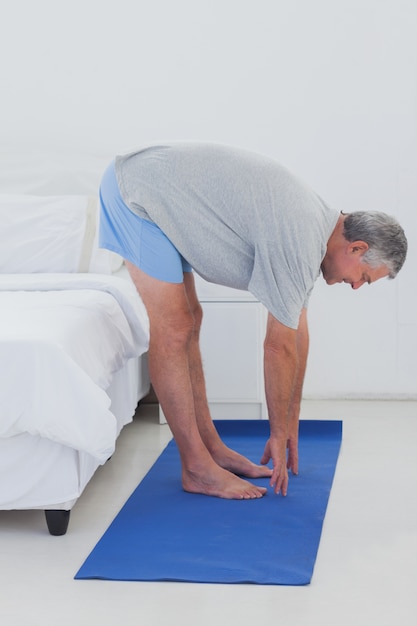 Volwassen man die zich uitstrekt over een aerobic mat