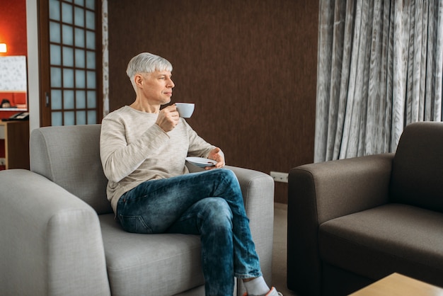 Volwassen man drinkt koffie en leest de krant