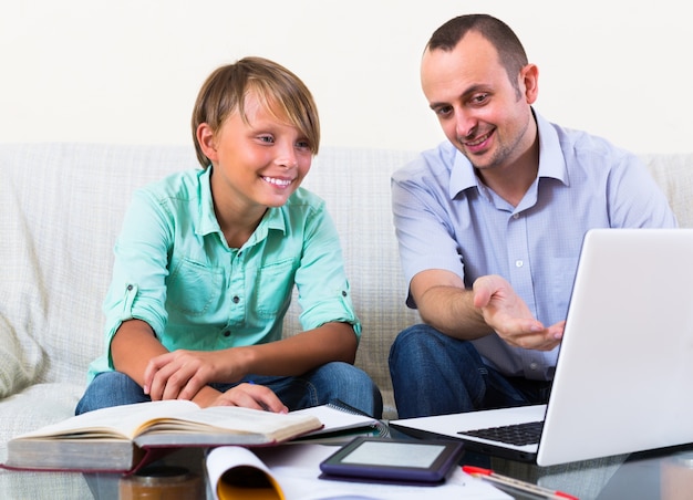 Volwassen man en jongen met laptop binnenshuis