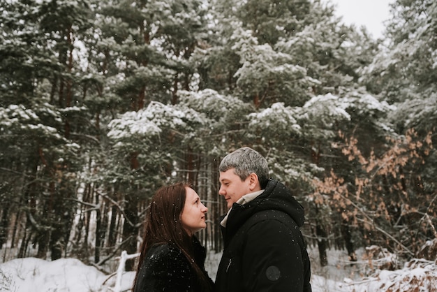 Volwassen man en vrouw op de achtergrond van een winter met sneeuw bedekte dennenbos