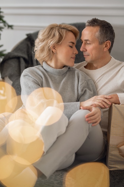 volwassen man en vrouw zitten op de grond bij de bank en knuffelen