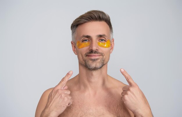 Volwassen man gezicht met collageen oog pleister schoonheid cosmetica geïsoleerd op blauw