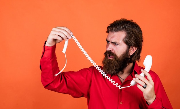 Foto volwassen man houdt gebroken retro telefoon vast man met baard en snor die de oproep beantwoordt telefoongesprek bebaarde man communicatie in het moderne leven spreek met vriend aan de telefoon