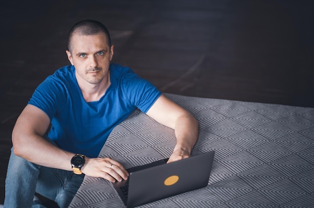 Foto volwassen man in blauwe t-shirt die op laptop werkt