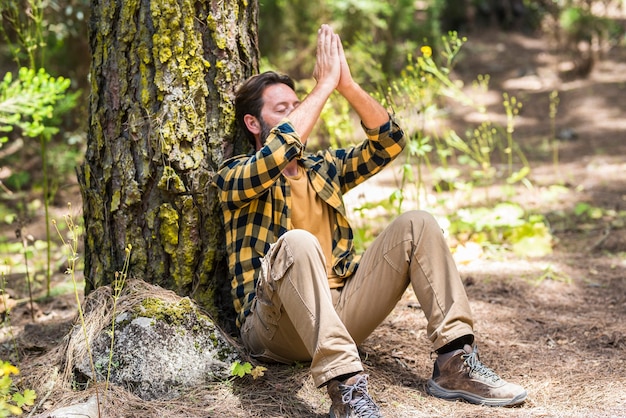 Volwassen man in het bos zittend op de grond meditatie doen en verliefd worden op bossen in de buitenlucht natuur rondom - concept van gezonde levensstijl en gelukkige vreedzame mensen