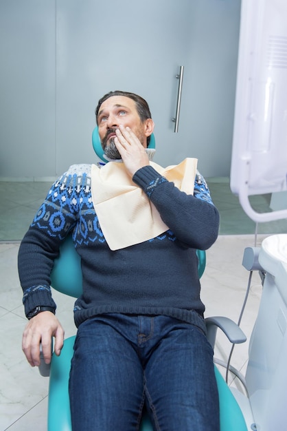 Volwassen man in tandartsstoel man met kiespijn tandbederf symptomen
