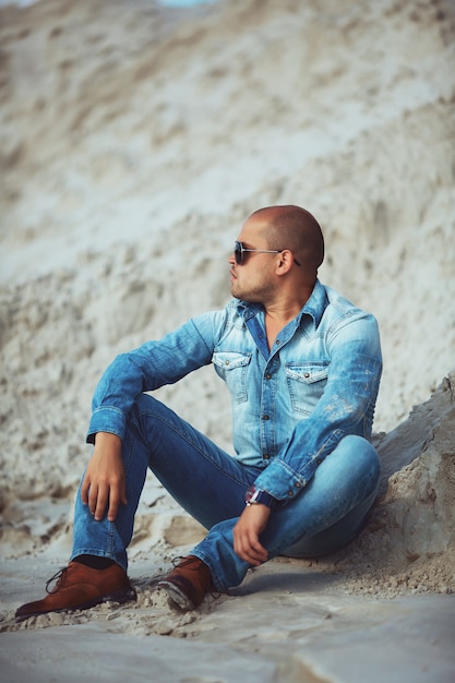 Volwassen man liggend in jeans kleding in het zand in Brazilië