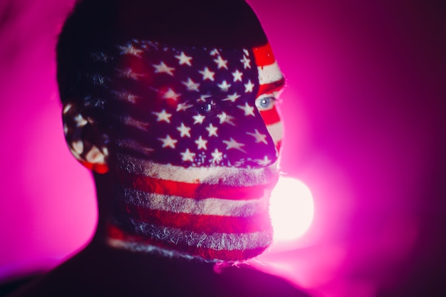 Volwassen man met Amerikaanse vlag op zijn gezicht in het donker.