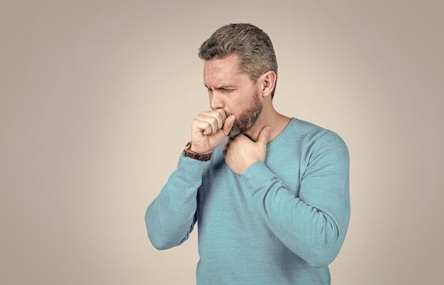 Volwassen man met baard heeft hoest last van keelpijn op grijze achtergrond mens gezondheid