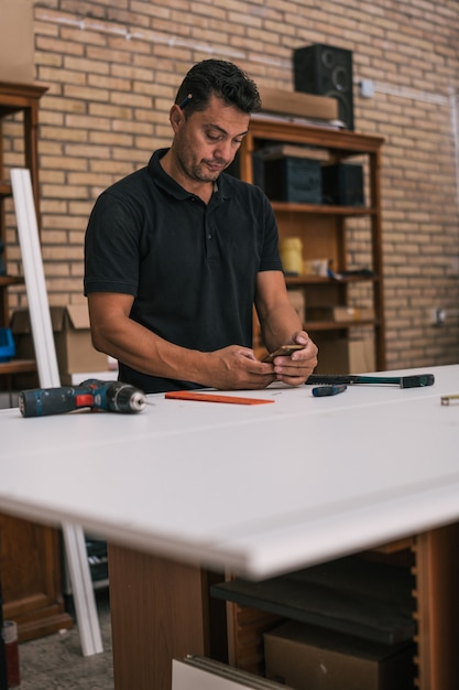 Volwassen man met behulp van een mobiele telefoon in een workshop