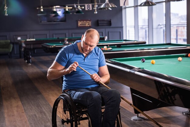 Volwassen man met een handicap in een rolstoel biljart in de club