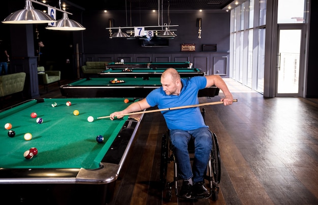 Volwassen man met een handicap in een rolstoel biljart spelen in de club
