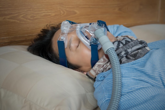 Volwassen man met een zuurstofmasker terwijl hij op bed slaapt