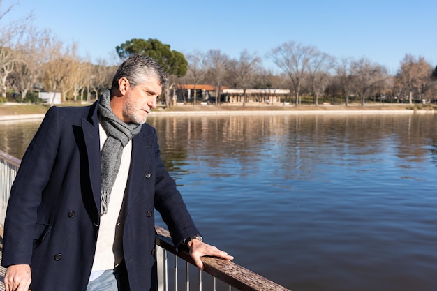 Volwassen man met jas die bij de rivier staat