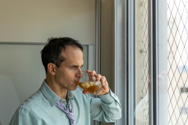 Volwassen man ontspannen met whisky na een lange dag op het werk (foto's in natuurlijk licht).