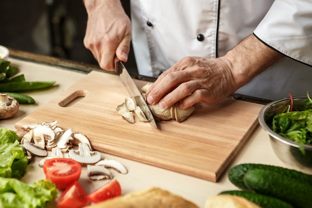 Volwassen man professionele chef-kok koken maaltijd binnenshuis