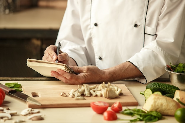 Volwassen man professionele chef-kok koken maaltijd binnenshuis