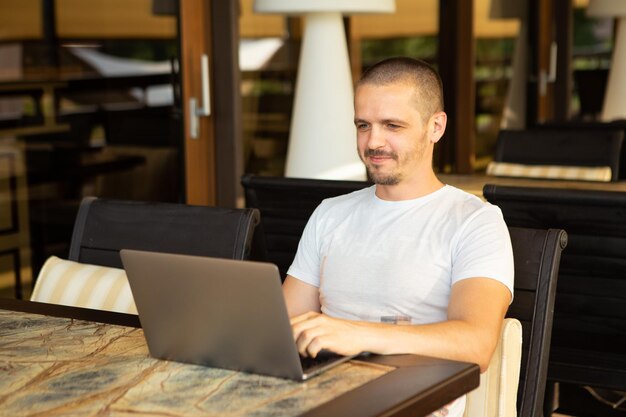 Volwassen man zit in restaurant of café en werkt op laptop. Freelancer aan het werk