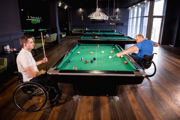 Volwassen mannen met een handicap in een rolstoel spelen biljart in de club