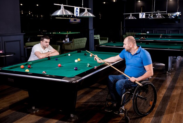 Volwassen mannen met een handicap in een rolstoel spelen biljart in de club