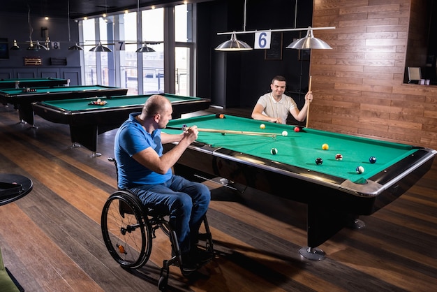 Volwassen mannen met een handicap in een rolstoel spelen biljart in de club