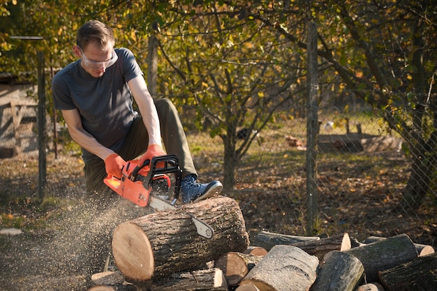 Foto volwassen mannetje dat hout snijdt met een elektrische kettingzaag