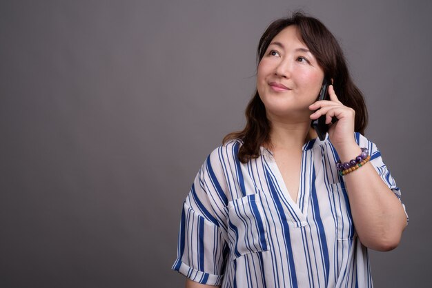 volwassen mooie Aziatische zakenvrouw met behulp van mobiele telefoon