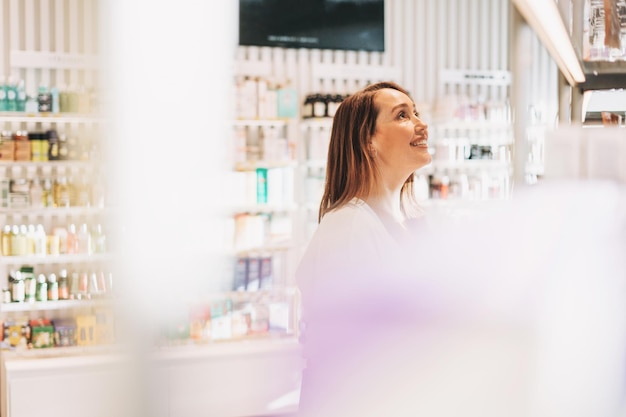 Foto volwassen mooie glimlachende vrouw met donker haar in cosmetica en parfum winkel vakantie winkelen