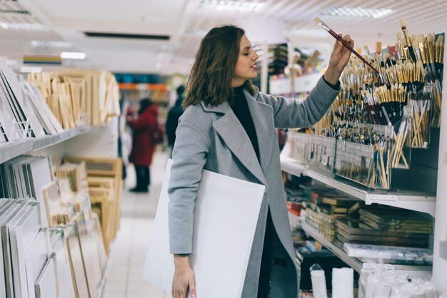 Volwassen mooie vrouw die penseel in kantoorboekhandel koopt