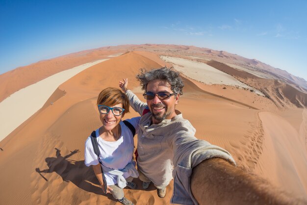 Volwassen paar die selfie op zandduinen in Sossusvlei in de Namib-woestijn nemen