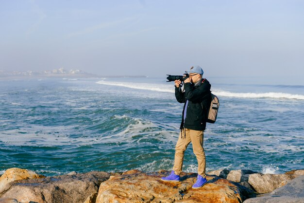 Volwassen reizigersmens die een foto van mooi landschap van oceaankaap in portugal met beroeps in zonnige ochtend nemen.