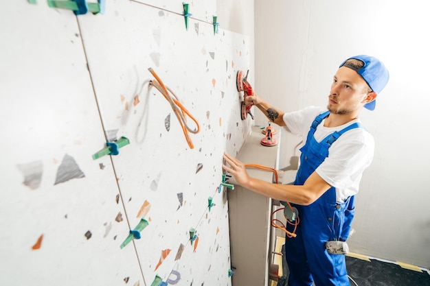 Volwassen reparateur in een speciaal uniform die tegels op de muur legt in de badkamer in een nieuw huis