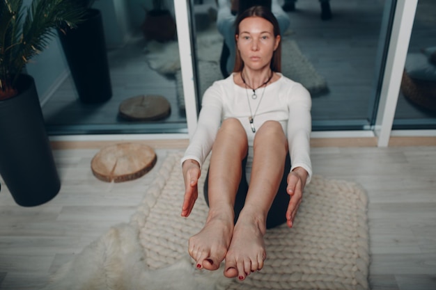 Volwassen rijpe vrouw doet yoga thuis woonkamer met online tutorials op laptop