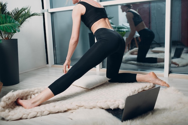 Volwassen rijpe vrouw doet yoga thuis woonkamer met online tutorials op laptop