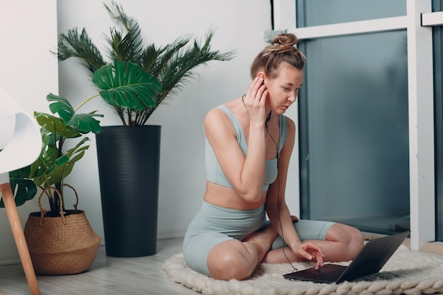 Volwassen rijpe vrouw doet yoga thuis woonkamer met online tutorials op laptop