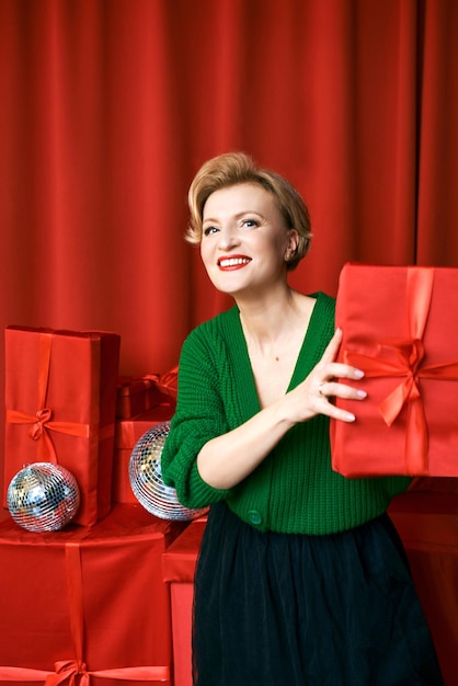 volwassen stijlvolle elegante vrouw met geschenkdoos op rode achtergrond. Feest, mode, feest, anti-leeftijd!