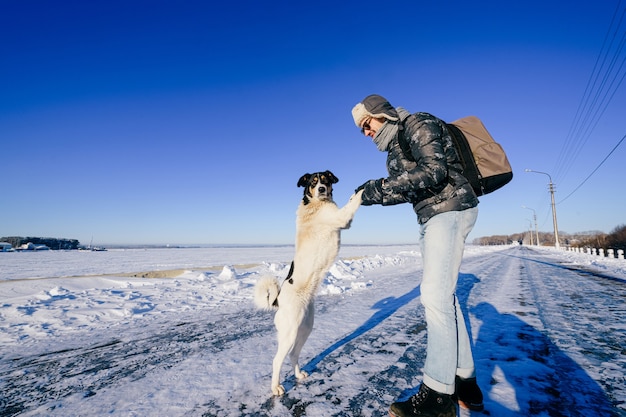 Volwassen stijlvolle man poseren met vriendelijke hond in het sneeuwveld