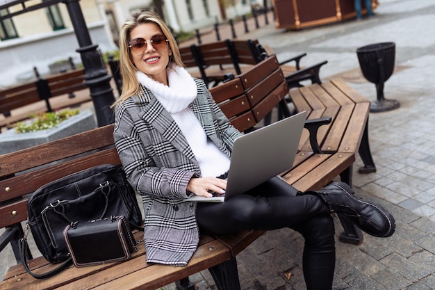 Volwassen succesvolle vrouwelijke ondernemer die online aan laptops op het stadsplein werkt