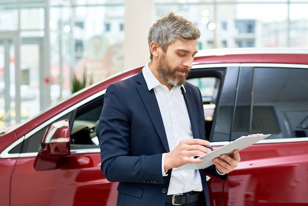 Volwassen verkoopassistent in autoshowroom