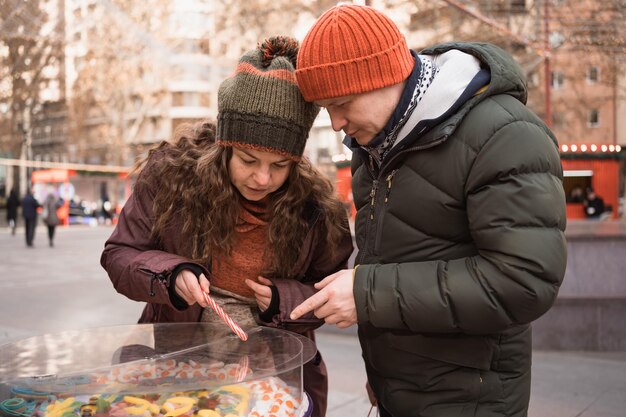 Volwassen verliefde paar die snoep kiezen bij candybar op straatmarkt tijdens de wintervakantie