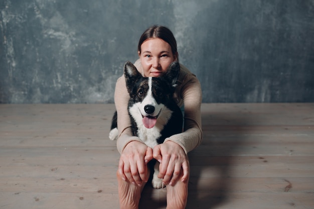 Volwassen volwassen vrouw doet yoga thuis in de woonkamer met het huisdier van de corgi-hond