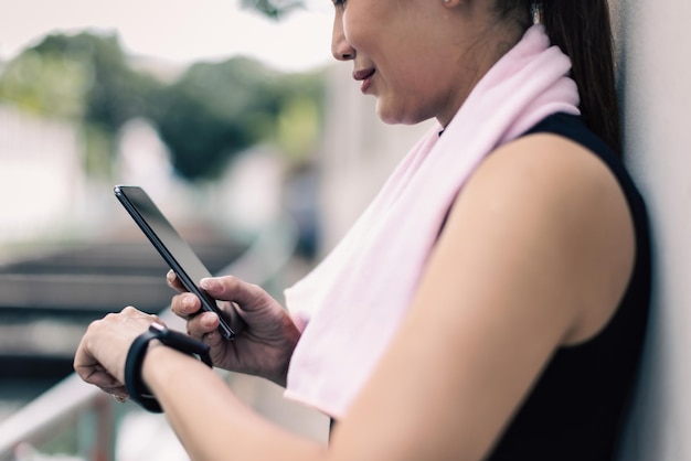 Volwassen volwassen vrouwen in sportkleding vergelijken, synchroniseren of lezen resultaten van fitnessapplicatie op het scherm van smartphone en smartwatch-apparaten na training of training. Concept van goede gezondheidszorg.