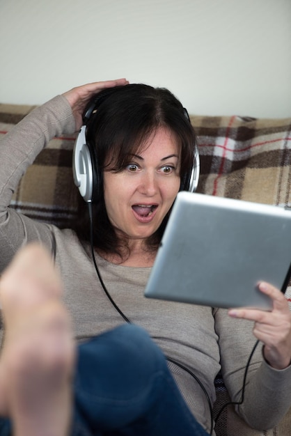 Foto volwassen vrouw die een digitale tablet gebruikt terwijl ze thuis zit