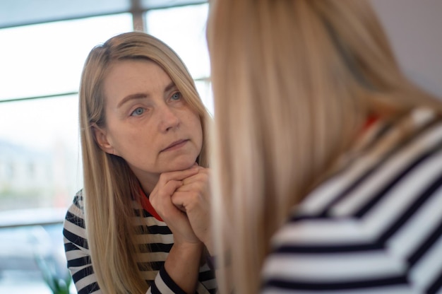 Foto volwassen vrouw die in de spiegel kijkt.