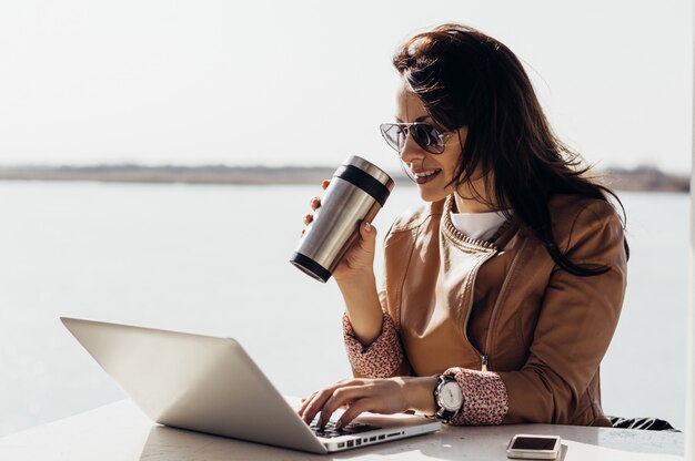 Volwassen vrouw die op afstand werkt. Freelancen buitenshuis. Vrouw koffie drinken en buiten werken aan laptopcomputer