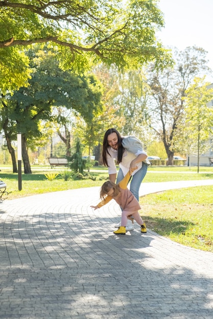 Volwassen vrouw die plezier heeft met het inhalen van haar kinddochter in groen park