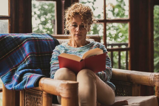 Foto volwassen vrouw die thuis een boek leest